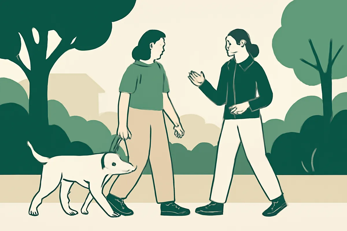 A trainer walking and talking with a client and her dog along a leafy street